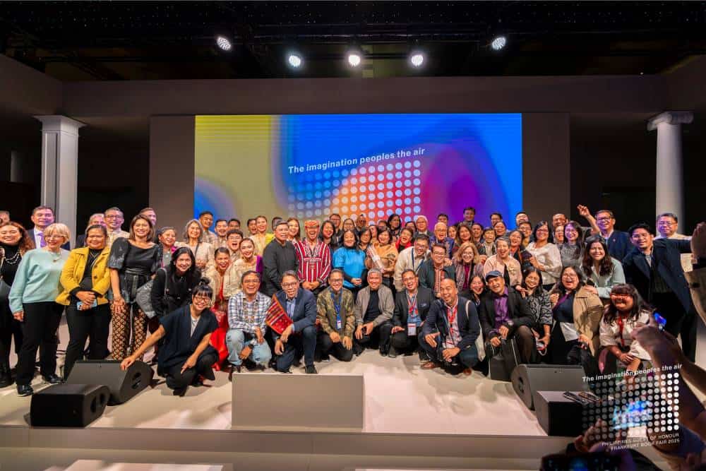 The Philippine delegation stands together on stage, smiling. A screen behind them displays the colorful graphics of the theme.