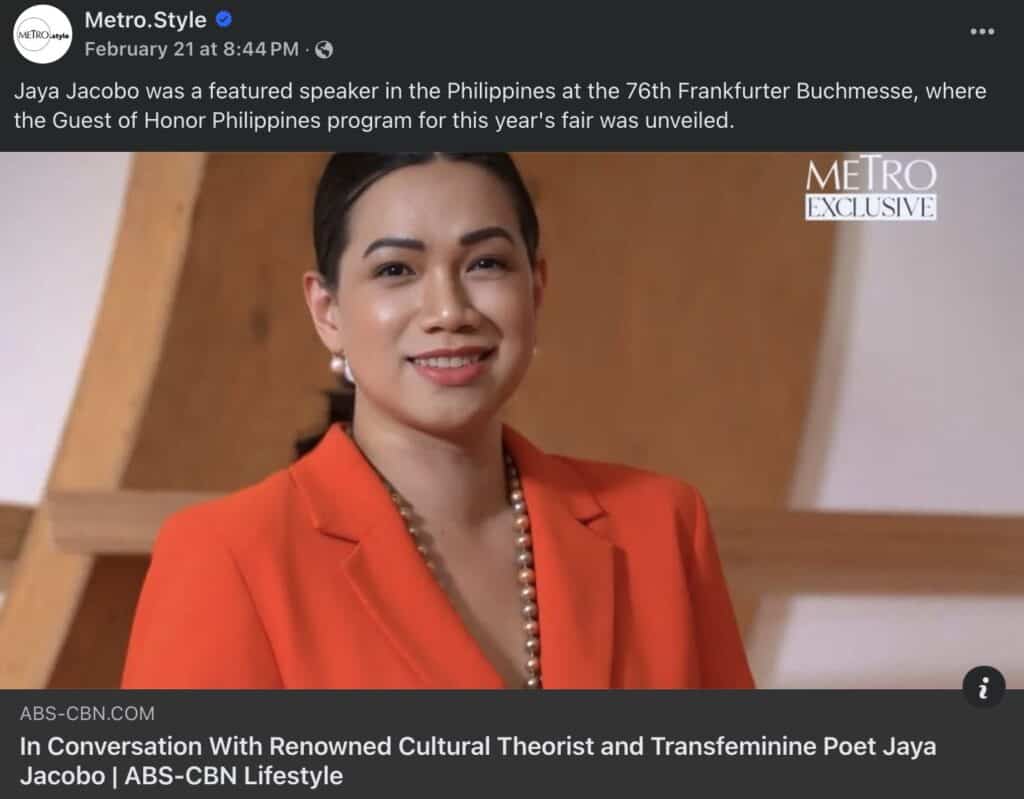 Jaya Jacobo, speaker at the Frankfurter Buchmesse, in an orange blazer stands indoors, smiling.