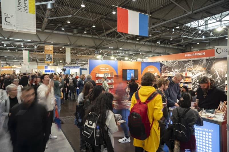 A crowded convention hall at the Leipzig Book Fair with people walking past a book display at the Philippines booth