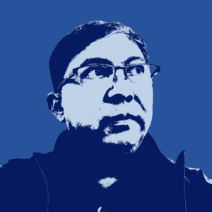 High-contrast, blue-tinted portrait of a person with short hair and glasses, looking slightly to the side, wearing a collared jacket.
