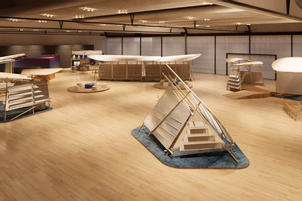 Spacious indoor exhibition with modern wooden structures and installations on a light wood floor, under a high ceiling with spotlights.